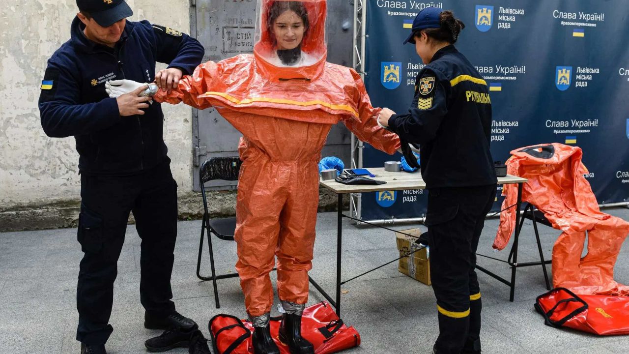 Так у вересні 2022 року українські надзвичайники допомогли жінці одягнути захисний костюм під час навчань з ядерної аварії у Львові.